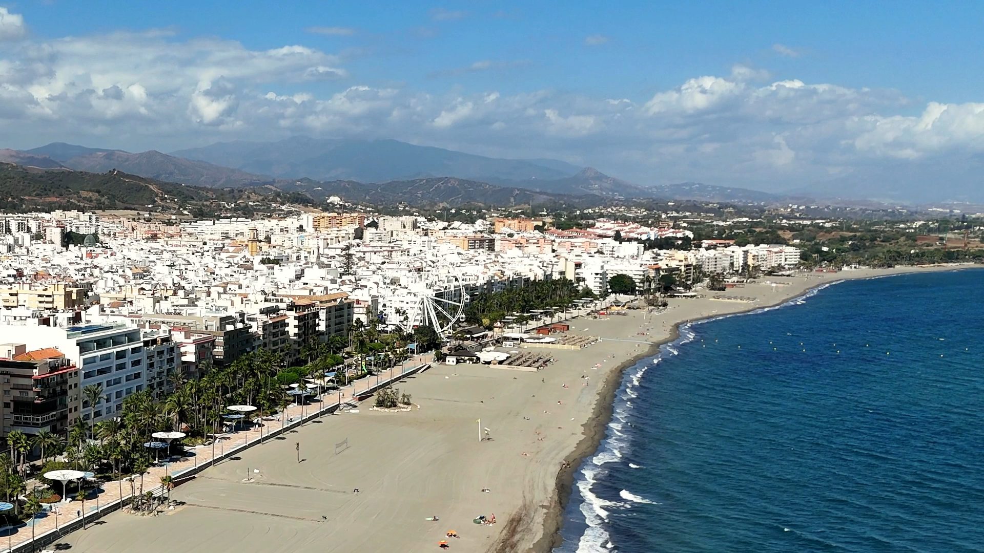 Vista aérea del paseo marítimo y la playa de Estepona, con la sierra al fondo