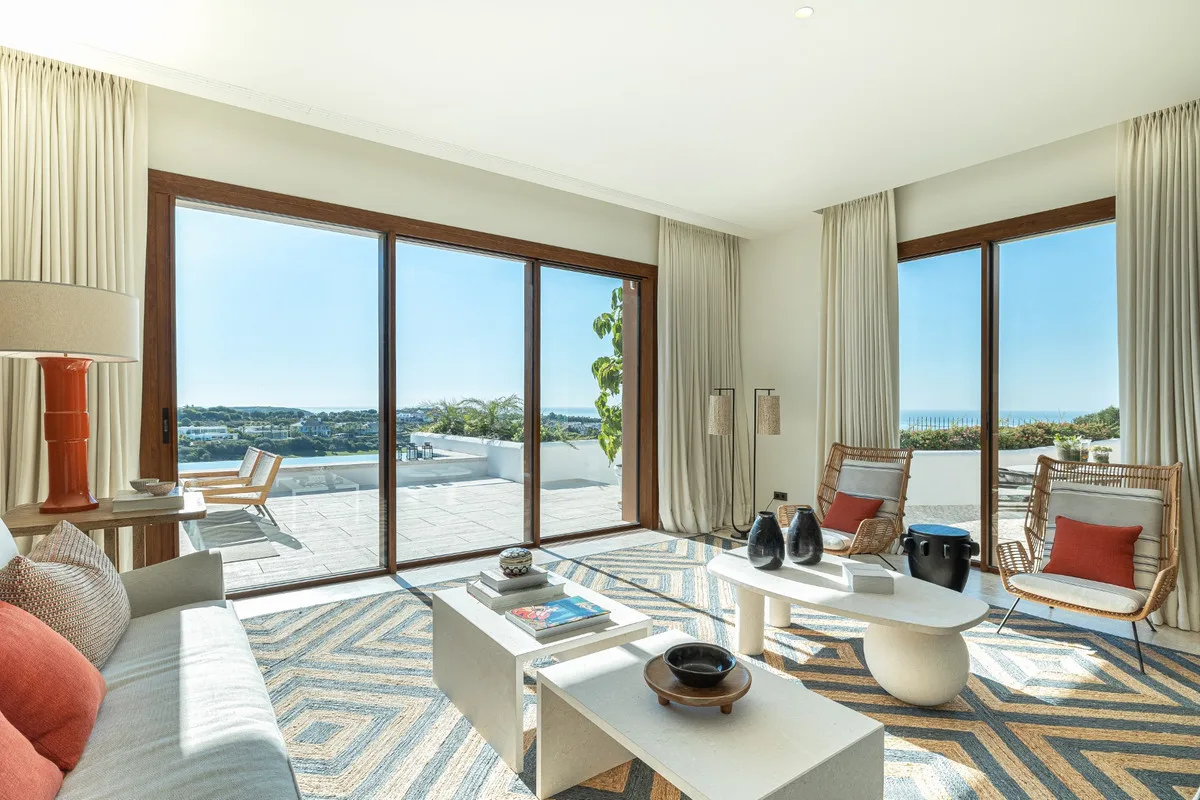 Salón luminoso con grandes ventanales a la terraza y vistas al golf y al mar, en Finca Cortesín