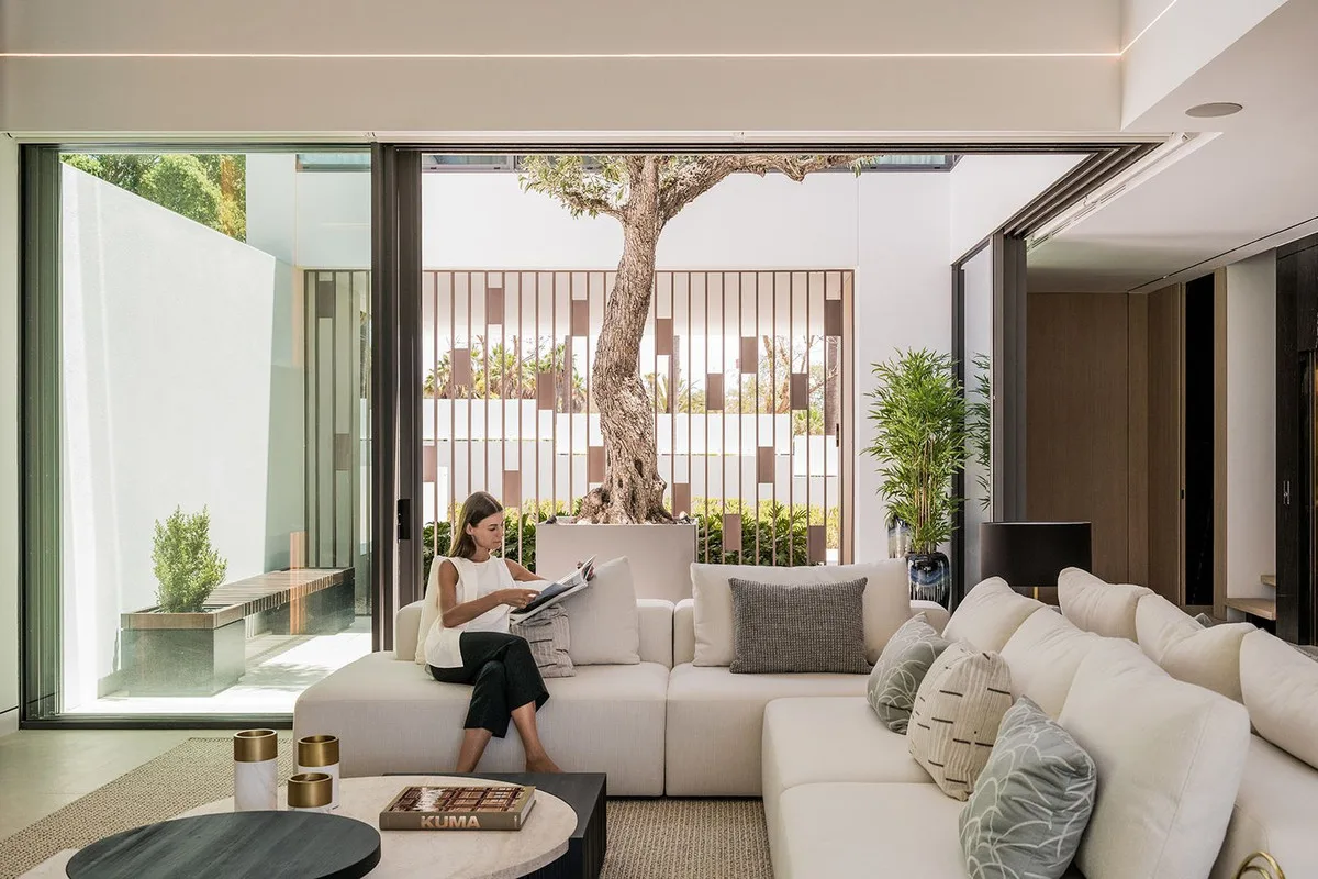 Salón abierto a un patio con olivo, en una villa contemporánea de Marbella