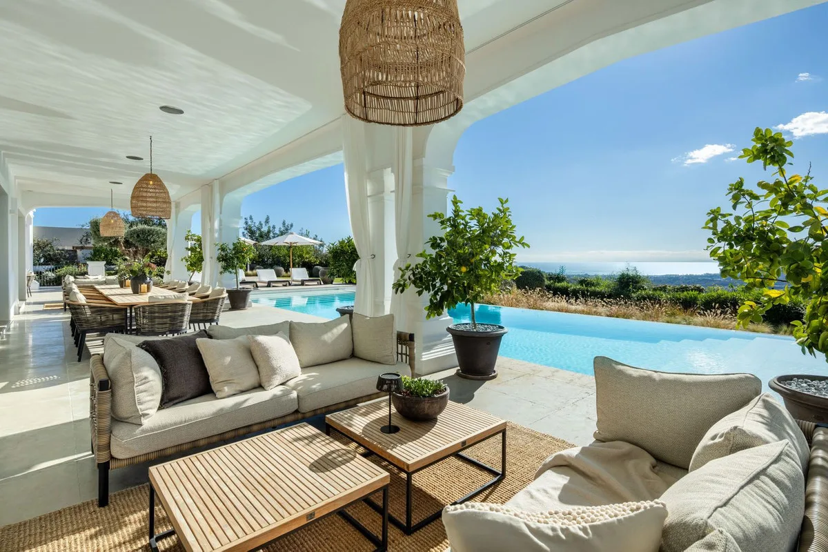 Porche con salón exterior sobre la piscina y la costa, en una casa andaluza de Marbella Club Golf Resort, Benahavís